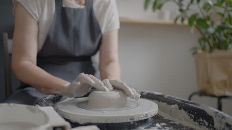 Elderly-woman-master-works-on-a-potter's-wheel-and-makes-a-mug-of-ceramics-in-her-workshop-in-slow-motion